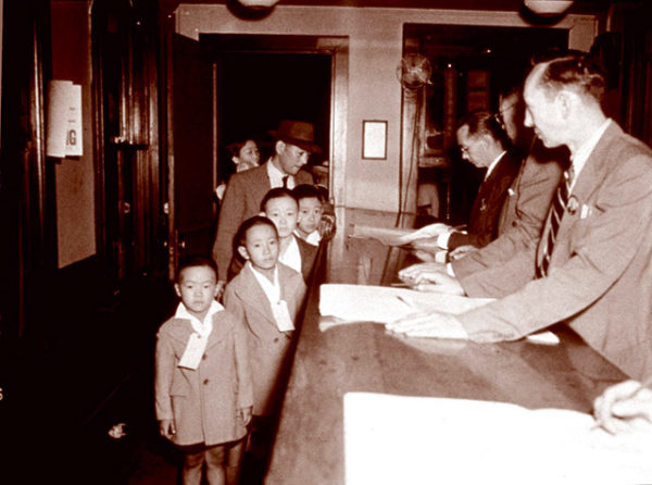 Japanese Peruvian boys wearing ID tags being processed for deportation, ca 1943